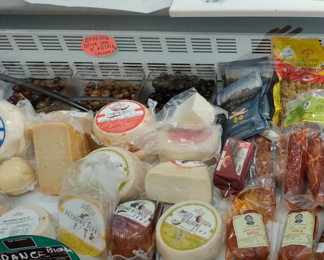 Il banco frigo di Natural Fruit: forme di pecorino pepato, pecorino affinato e Bergorino, provole e mozzarelle, le vaschette di olive e, sulla destra, la ’nduja e la salsiccia