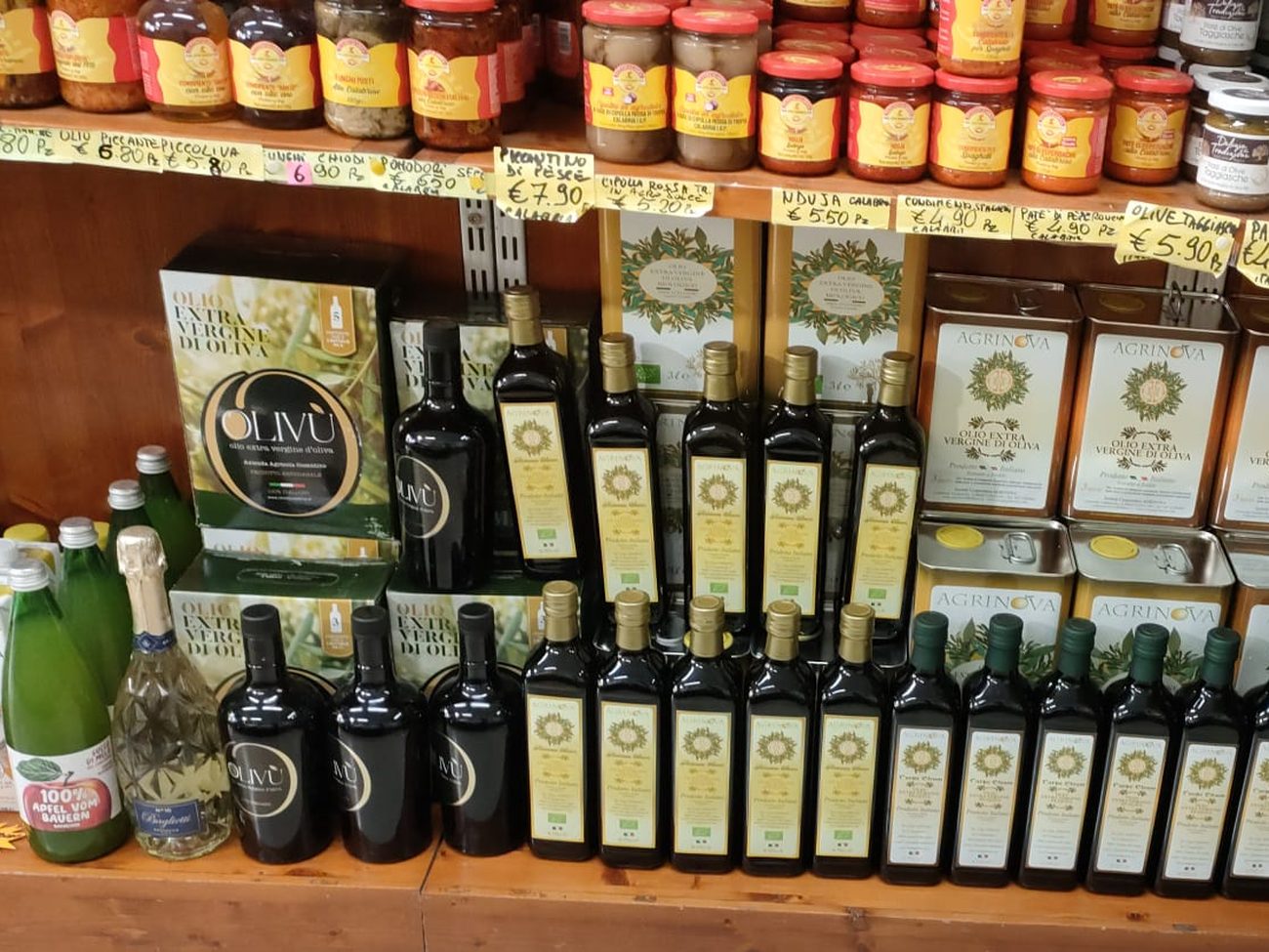 Lo scaffale dell’olio extravergine di Natural Fruit: le confezioni e le bottiglie OLIVÙ, le latte Agrinova e le file di bottiglie di extravergine