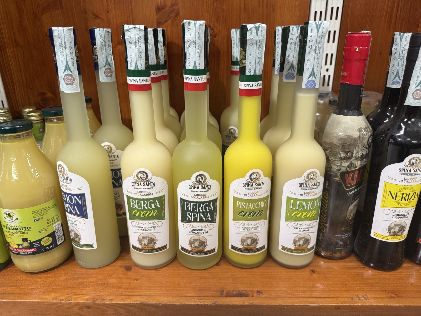 Bottiglie di succo, creme e liquori di bergamotto di Calabria sullo scaffale di Natural Fruit