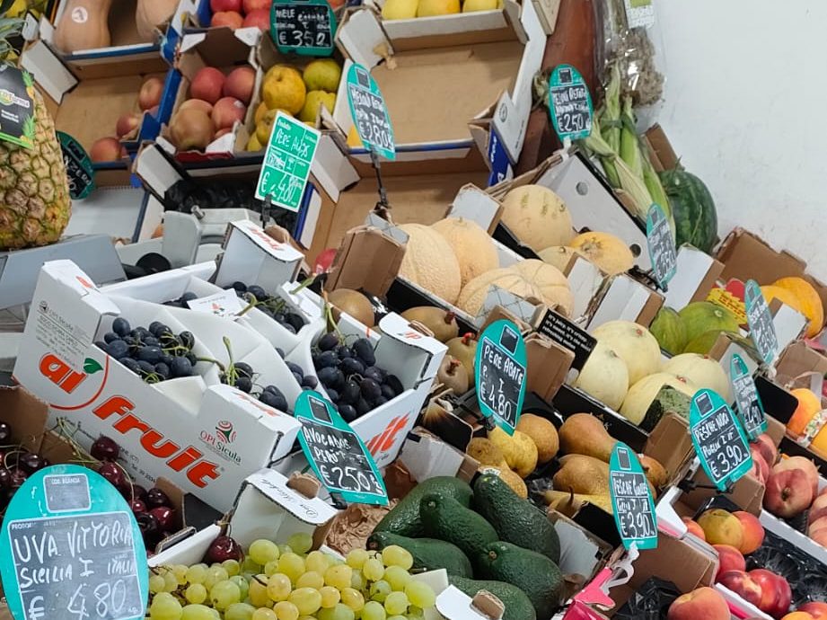 Il banco della frutta di Natural Fruit con uva, avocado, pesche, pere e meloni in cassetta