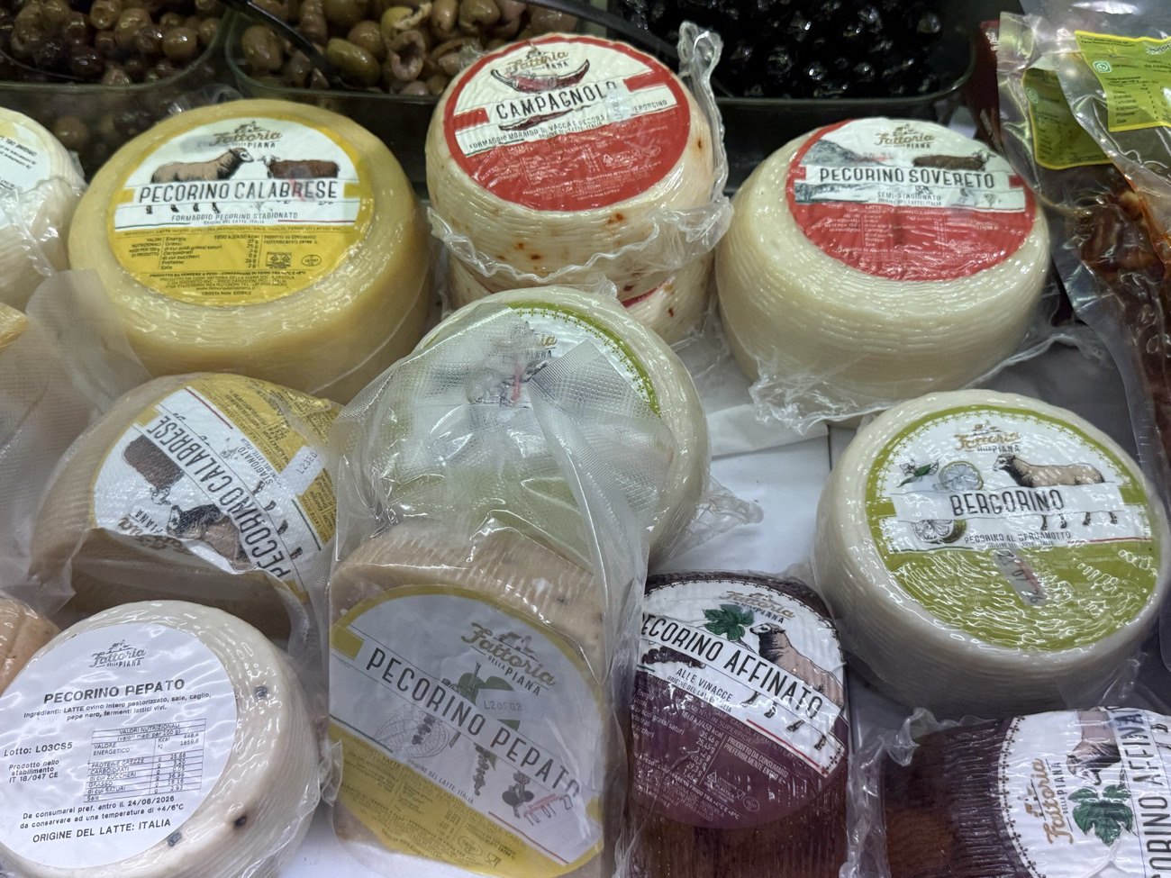 Forme di pecorino calabrese, pecorino pepato, pecorino affinato alle vinacce e Bergorino al bergamotto nel banco frigo di Natural Fruit